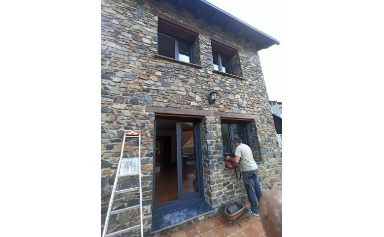 Instal·lació de finestres en un xalet amb façana de pedra a la Massana